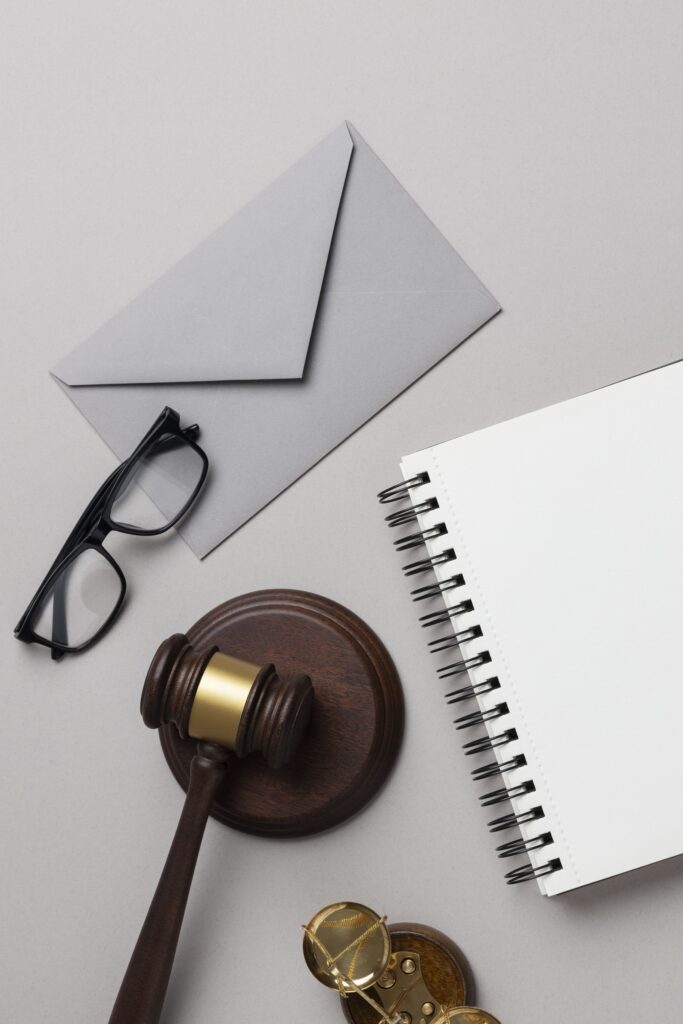Mazo, balanza, sobre y cuaderno sobre un escritorio representando el compromiso de Lemnis Abogadas con la justicia y la equidad en el asesoramiento y representación en Derecho Laboral.